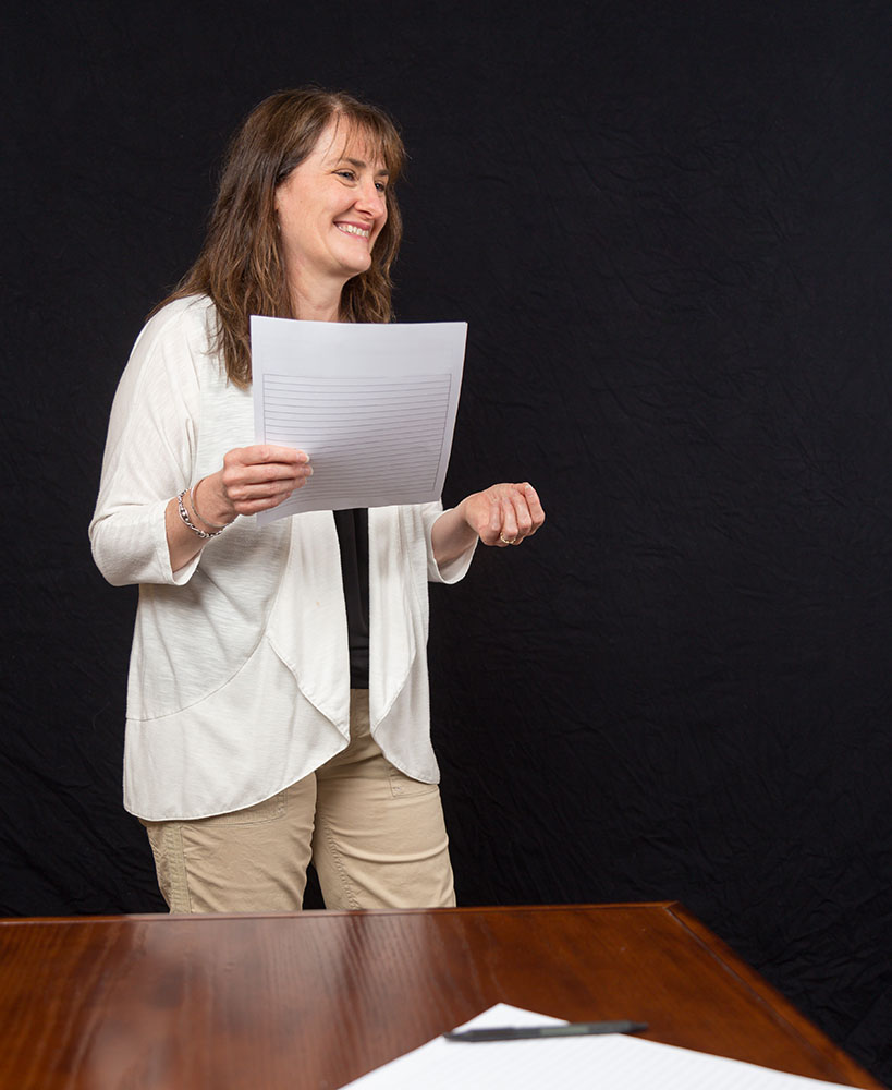 Photo of IGNITE Peak Performance certified elite coach Dr. Stephen holding papers in an office laughing and looking off to the right