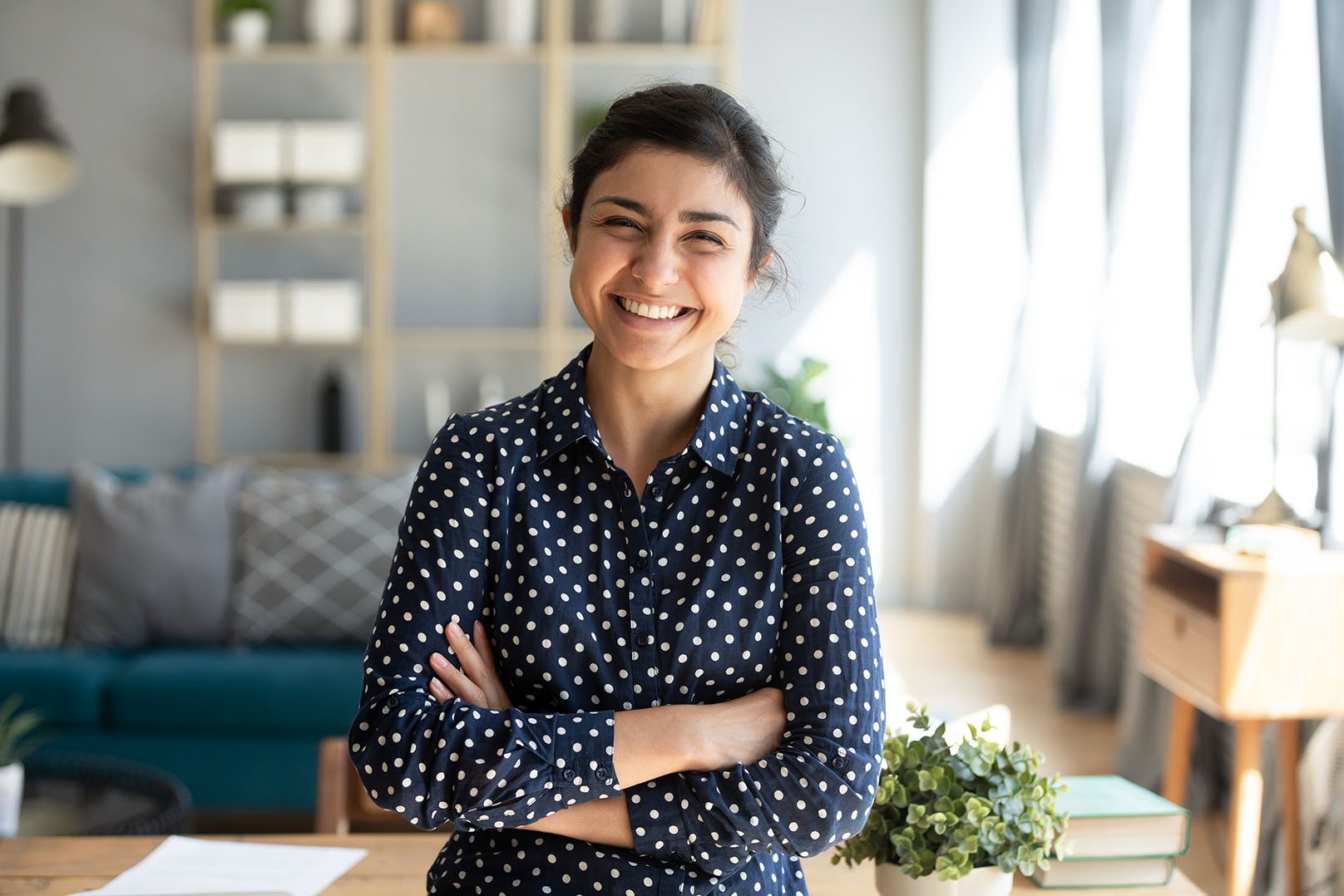Personal and Life Professional woman standing in living room in a navy shirt, crossing her arms and smiling at the camera for personal and life IGNITE Peak Performance coaching service