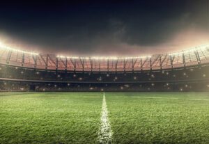 Photo of empty soccer stadium with green grass and lit up at night