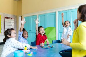 Children raising hands in classroom showing gendered attention in classrooms