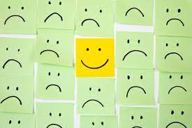 Stick note with a smiley face surrounded by sticky notes with frowny faces to symbolise identifying toxic positivity