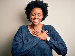 Woman with hands over her heart smiling to symbolise identifying toxic positivity