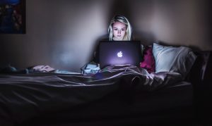 Girl sitting in bed at night on computer
