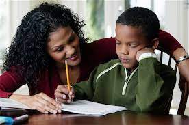 Mom sitting with child doing homework with him to signify giftedness