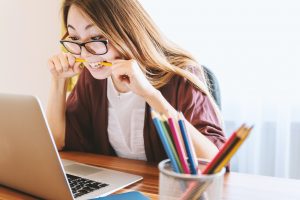 Woman at a desk biting a pencil to represent women doing the office housework