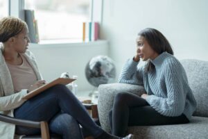 Young woman sitting on a sofa looking at a life coach