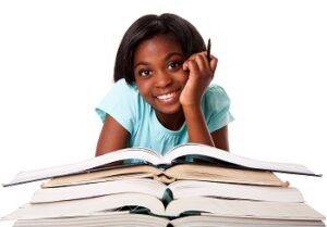 Girl smiling at camera over pile of open books