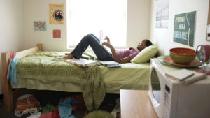 Image of young woman on dorm room bed