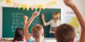 Children raising hands in classroom