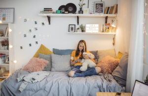 Young woman sitting on a dorm room bed