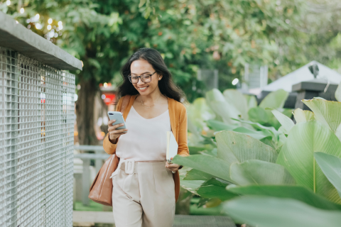 Woman outdoors smiling and looking at her phone