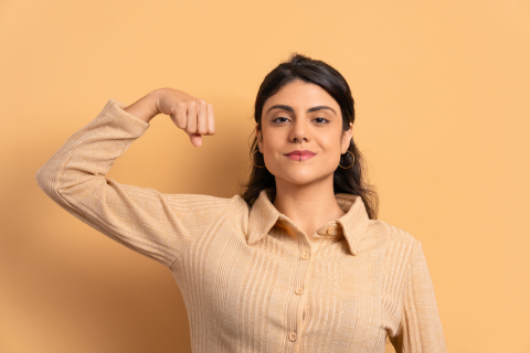 Happy and confident woman holding up arm to show muscle