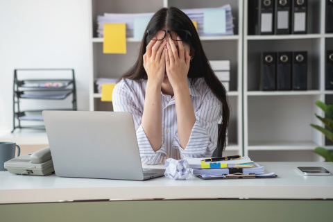 Photo of woman sitting at a desk with her head down in frustration