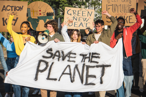Image of demonstrators holding signs with messages such as 'Save the Planet'