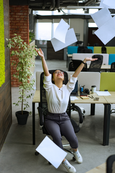Woman sitting in office chair throwing papers into the air to signify stress about finding your passion or growing it