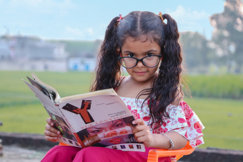 Image of child holding a book and looking up to to indicate giftedness