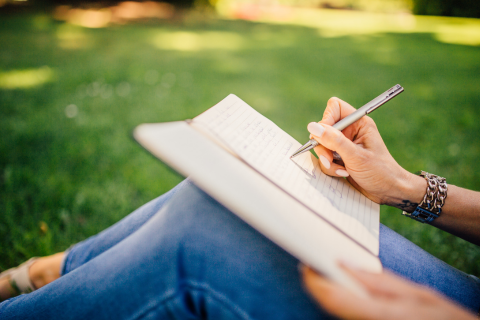 Woman journaling on a lawn
