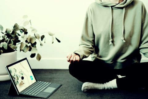 Image meditating woman near open laptop displaying meditation application