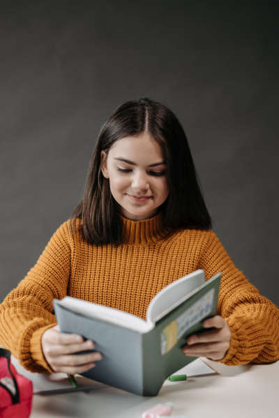 Girl smiling at while reading open book